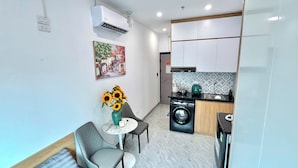 Uma cozinha compacta com máquina de lavar, área de jantar com mesa e cadeiras, e ar condicionado fixado na parede.