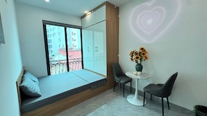 Quarto moderno com varanda, uma pequena mesa com cadeiras e projeção de luz em formato de coração na parede.
