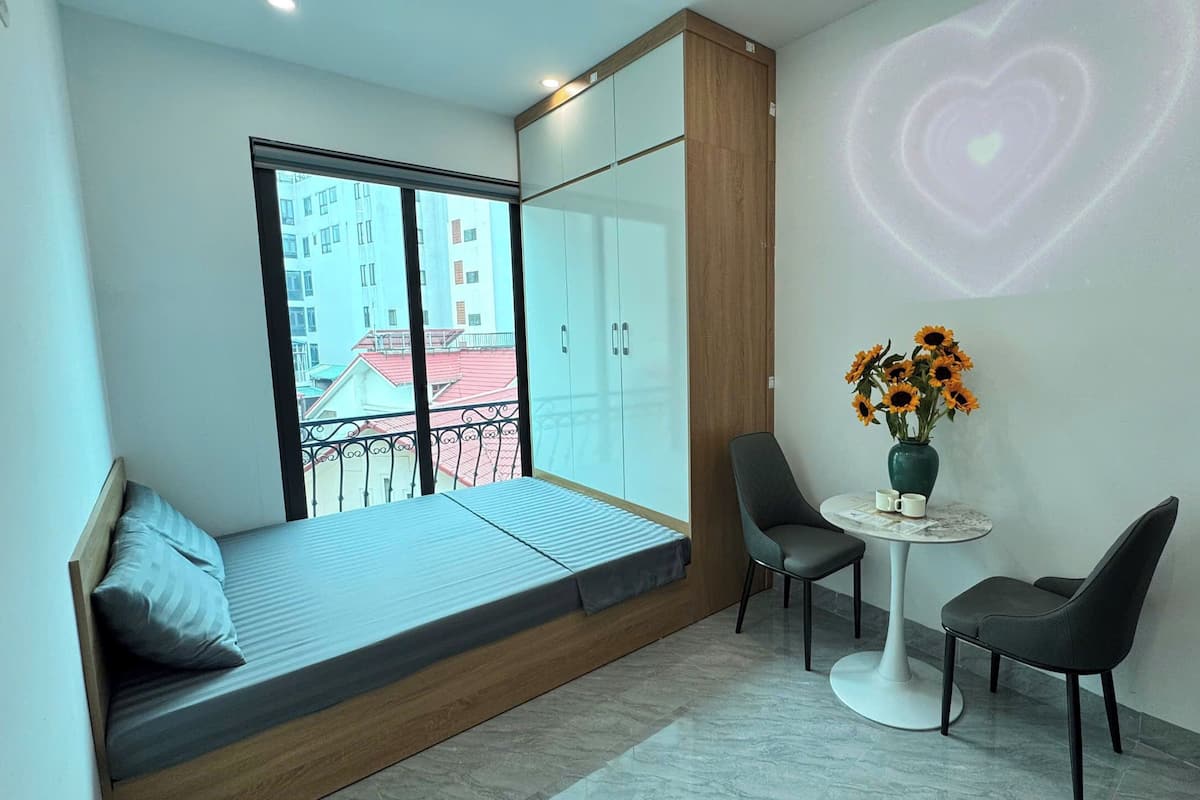 A modern room with a balcony, a small table with chairs, and a heart-shaped light projection on the wall.