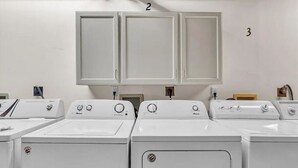 A laundry room with multiple washing machines and cabinets numbered 2 and 3. - Quiet West Plaza Retreat – Spacious Condo in Prime KC Location. (Kansas City)