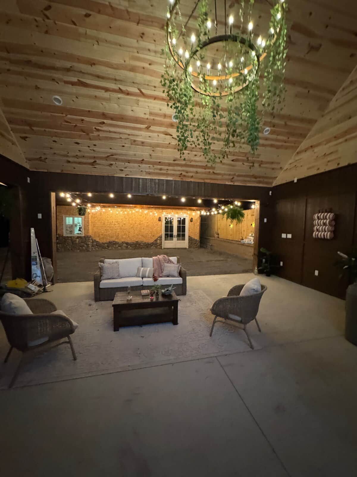 Un espace intérieur chaleureux avec un plafond en bois, un luminaire suspendu et un coin salon comprenant un canapé et des fauteuils.