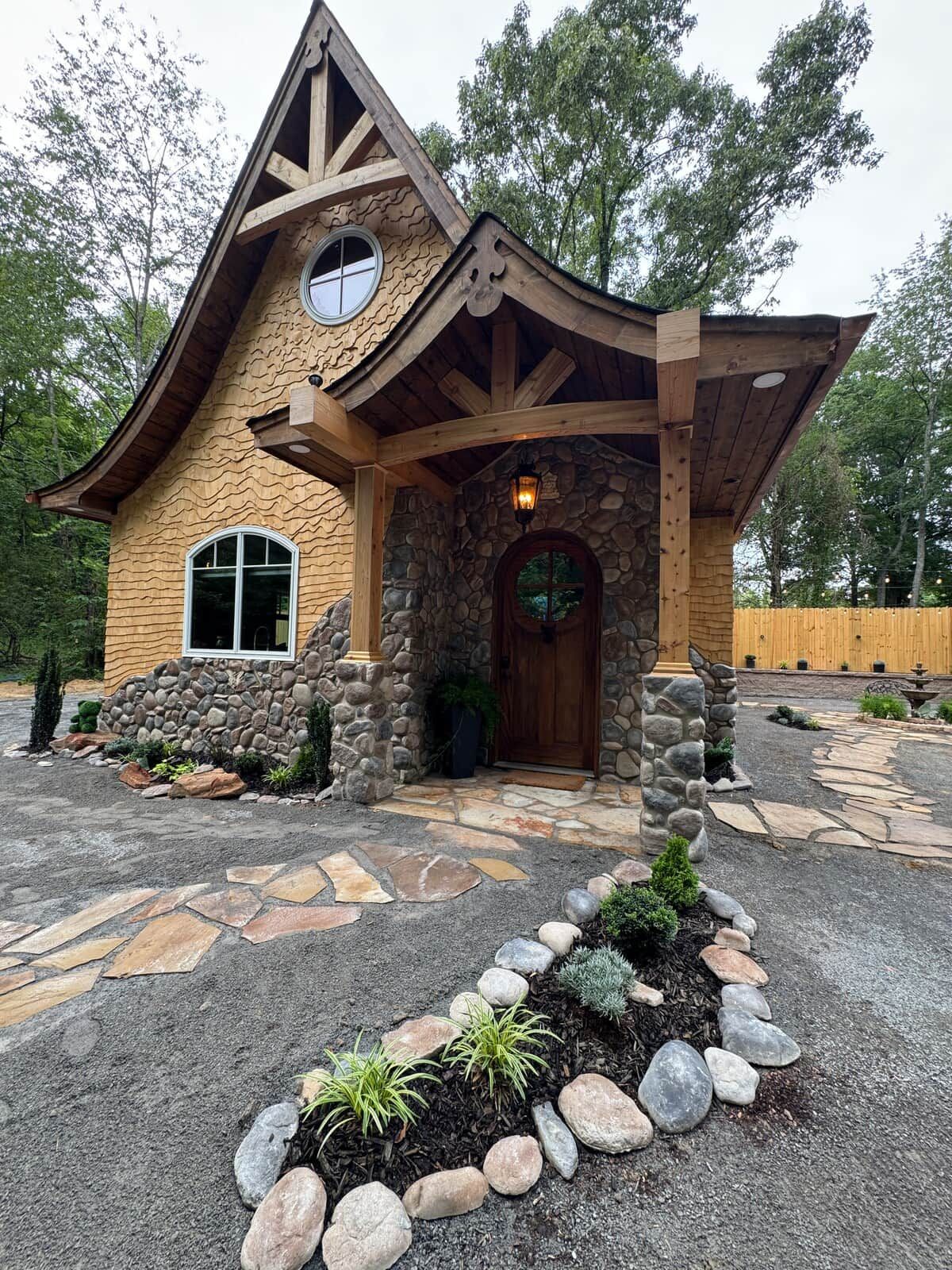 Una casa rústica con fachada de piedra, un porche de madera y una entrada de piedra.