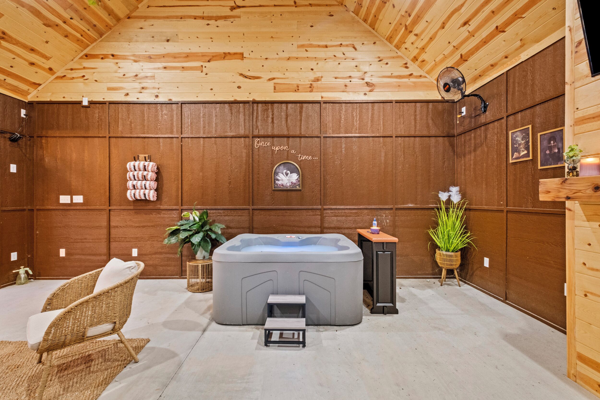 A wooden interior with a hot tub, wicker chair, and potted plants.