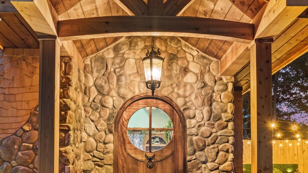 A stone facade with a wooden door, a stone staircase, and a stone pillar.