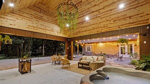 An outdoor patio area with a hot tub, wicker furniture, and a stone building in the background.