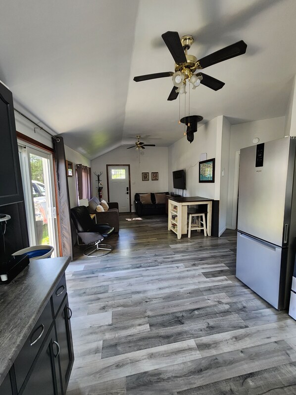 A spacious kitchen with a dining area, two ceiling fans, a refrigerator, and a dining table with chairs.