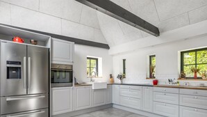 Una cucina moderna con elettrodomestici in acciaio inossidabile, mobili bianchi e un'ampia finestra che lascia entrare molta luce naturale.
