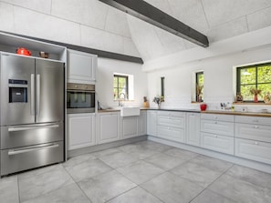 Eine moderne Küche mit Edelstahlgeräten, weißen Schränken und einem großen Fenster, das für natürliches Licht sorgt.