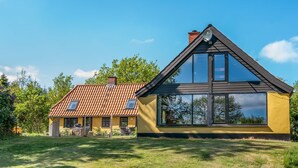 Una casa moderna con tetto spiovente, ampie finestre e un prato curato.