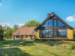 Ein modernes Haus mit einem geneigten Dach, großen Fenstern und einem gepflegten Rasen.
