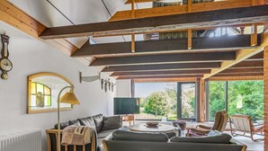Un soggiorno moderno con soffitto alto, un divano, un tavolino da caffè e vista sull'esterno.