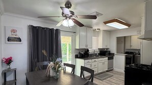 Una cocina moderna con comedor, ventilador de techo y vistas al exterior.