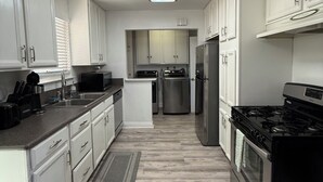Una cocina moderna con armarios blancos, una isla central, electrodomésticos de acero inoxidable y un tragaluz.