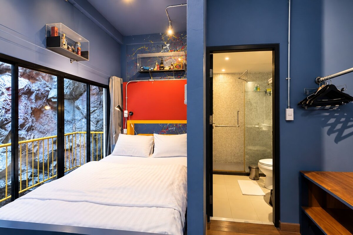 Un dormitorio con cama, un banco de madera, un baño con inodoro y ducha.