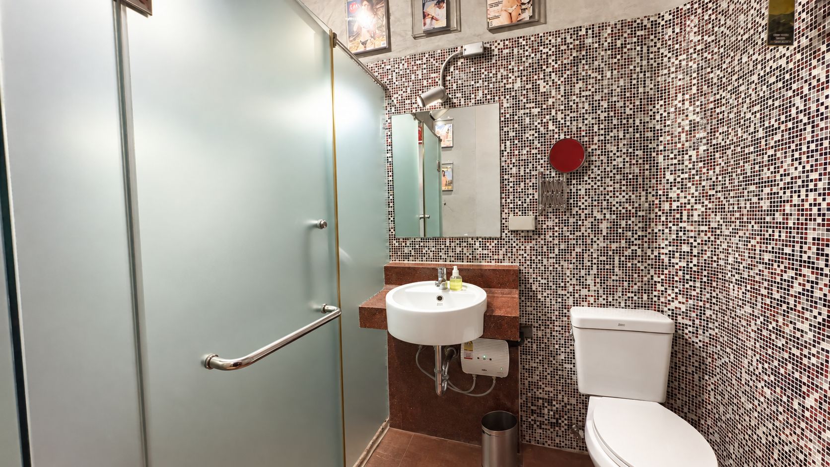 A bathroom with a glass shower door, a white sink, and a toilet.