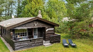 Une cabane rustique dotée d’une cheminée, d’une porte en verre et d’un petit espace porche.