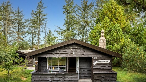 Une cabane rustique avec une cheminée, une fenêtre et une enseigne sur laquelle on peut lire « Kremerhuset ».
