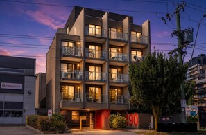 A multi-story building with balconies, a visible entrance, and a sign indicating a number. - Cozy Box Hill Studio Apt | Walk to Hospital & Rail (Box Hill)