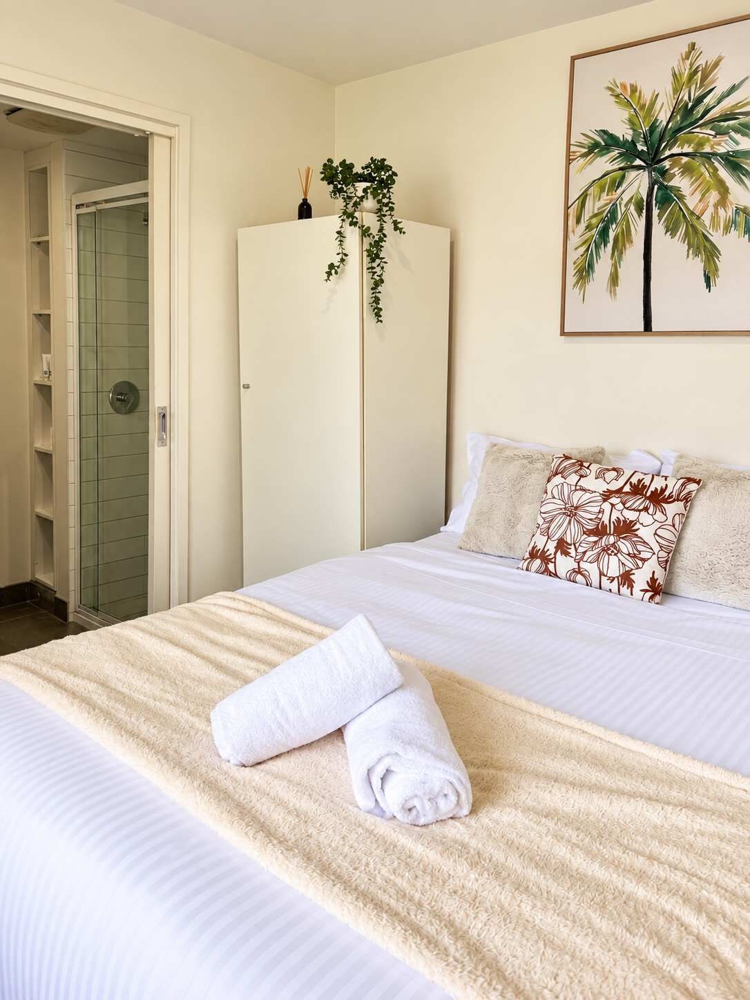 A hotel room with a bed, a white wardrobe, a door, and a framed picture on the wall.