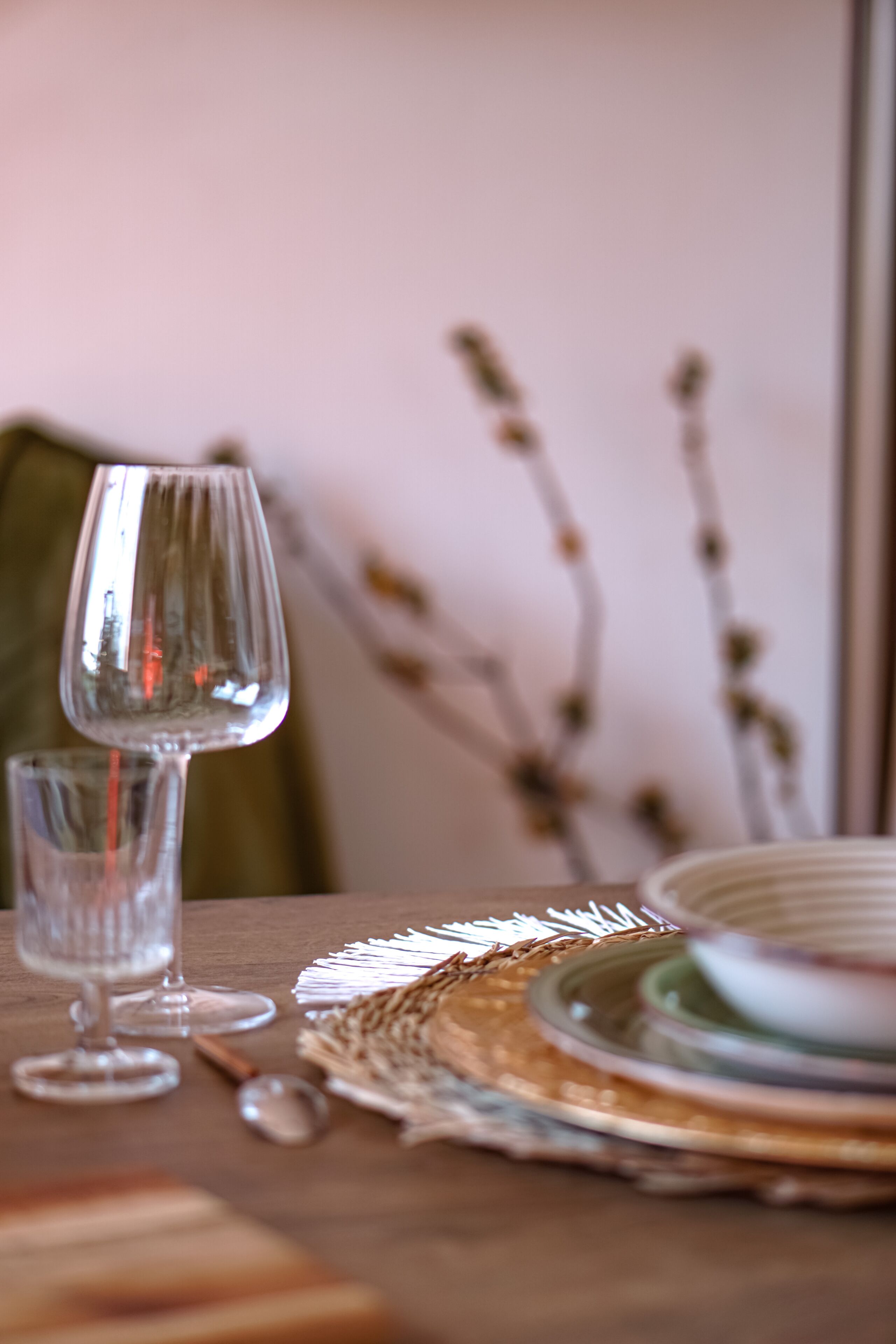 Een eettafel met een wijnglas, een klein schaaltje en een lepel.