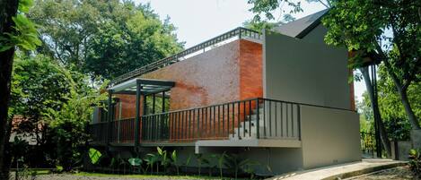 A modern building with a brick facade, a balcony, and a staircase leading to an upper level.