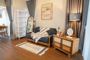 Una habitación acogedora con cama, mesita de noche de madera, lámpara, espejo, estante y una silla.