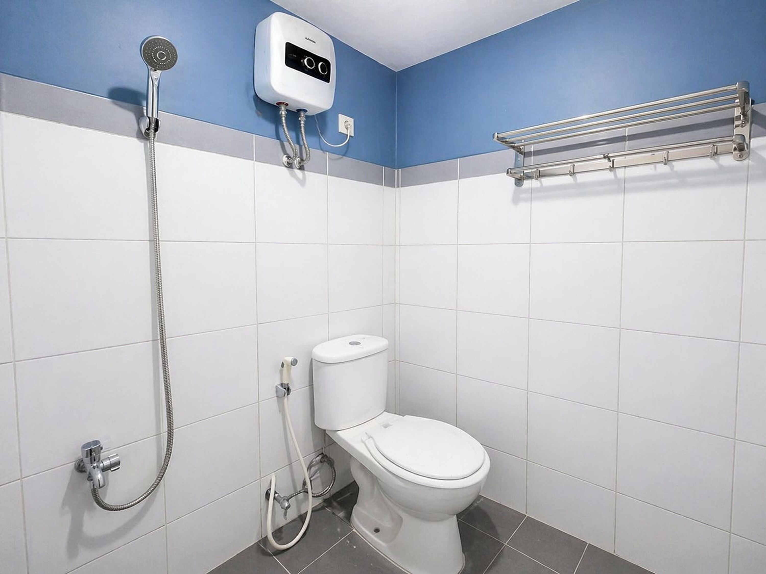 A bathroom with a toilet, a shower, and a hand dryer.