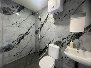 Une salle de bain avec des toilettes, un lavabo et une douche.