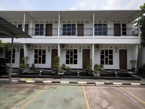 A two-story building with numbered doors, a covered entrance, and potted plants. - Nata Hotel Tasikmalaya (Tasikmalaya)