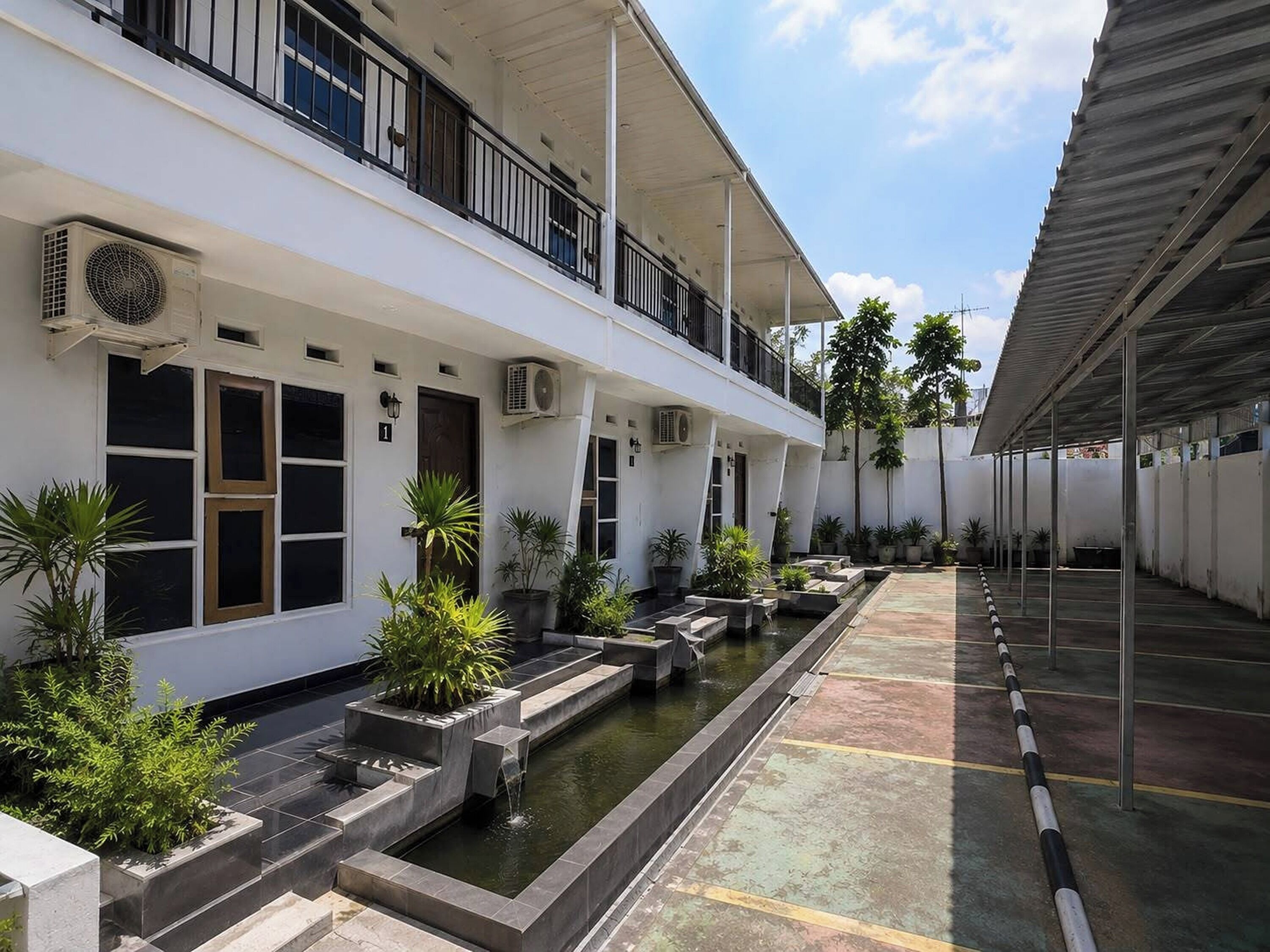 A building with multiple floors, outdoor seating, a water feature, and potted plants.