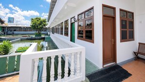A white building with a covered walkway, a green door, and a small pool. - Nata Hotel Tasikmalaya (Tasikmalaya)