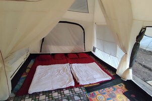 Uma tenda com uma cama, almofadas vermelhas e um tapete colorido no chão.