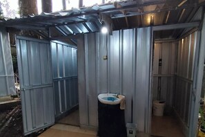 A small, enclosed bathroom with a single sink, a toilet, and a trash bin. - Youlien Campsite Bandung (Pasirjambu)