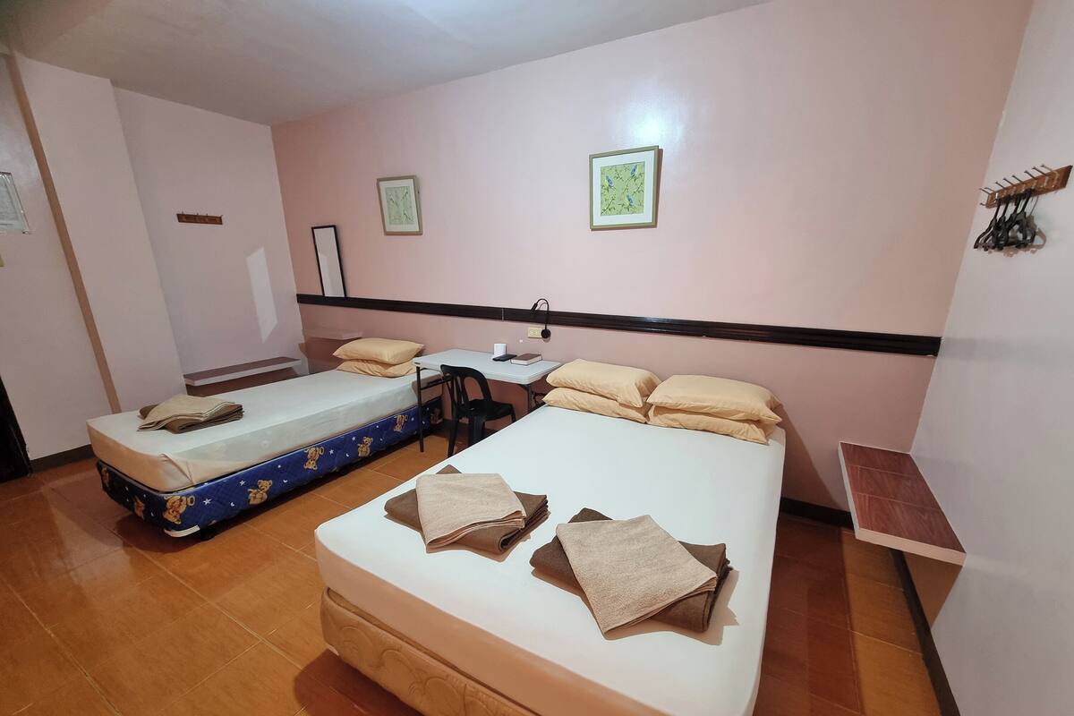 A hotel room with two beds, a desk, and a chair.