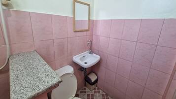 Un baño pequeño con inodoro, lavamanos y espejo.