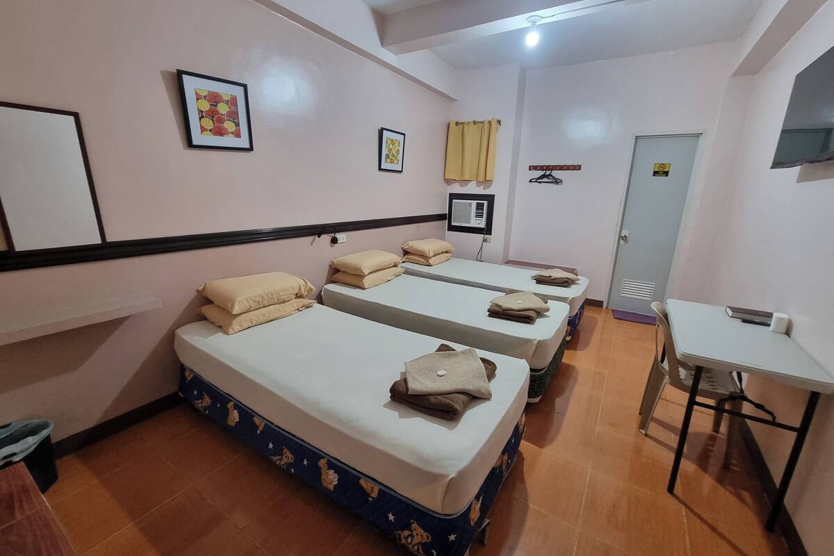 A room with three beds, a desk, a chair, and a door.
