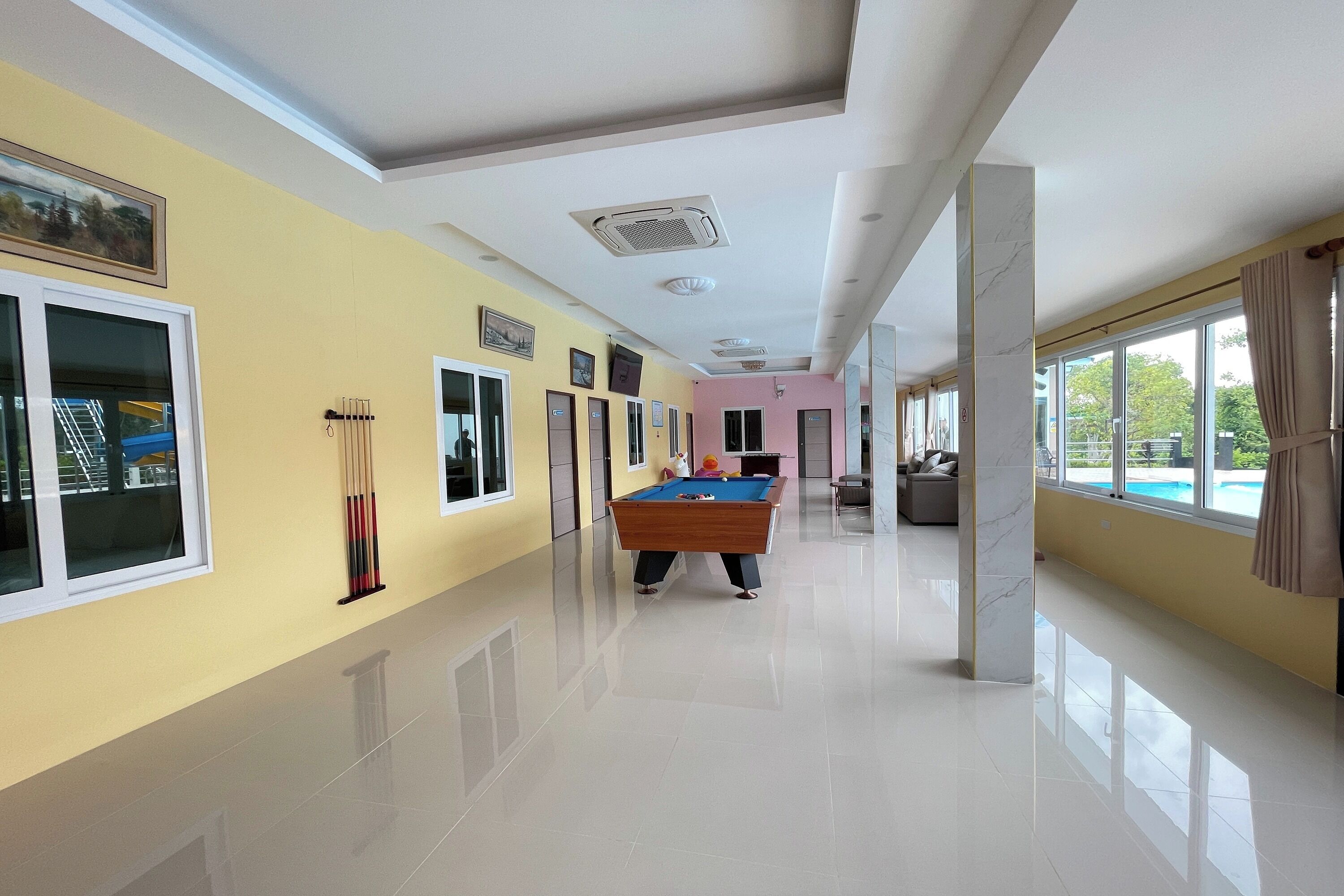 A hotel lobby with a pool table, large windows, and a clean, polished floor.