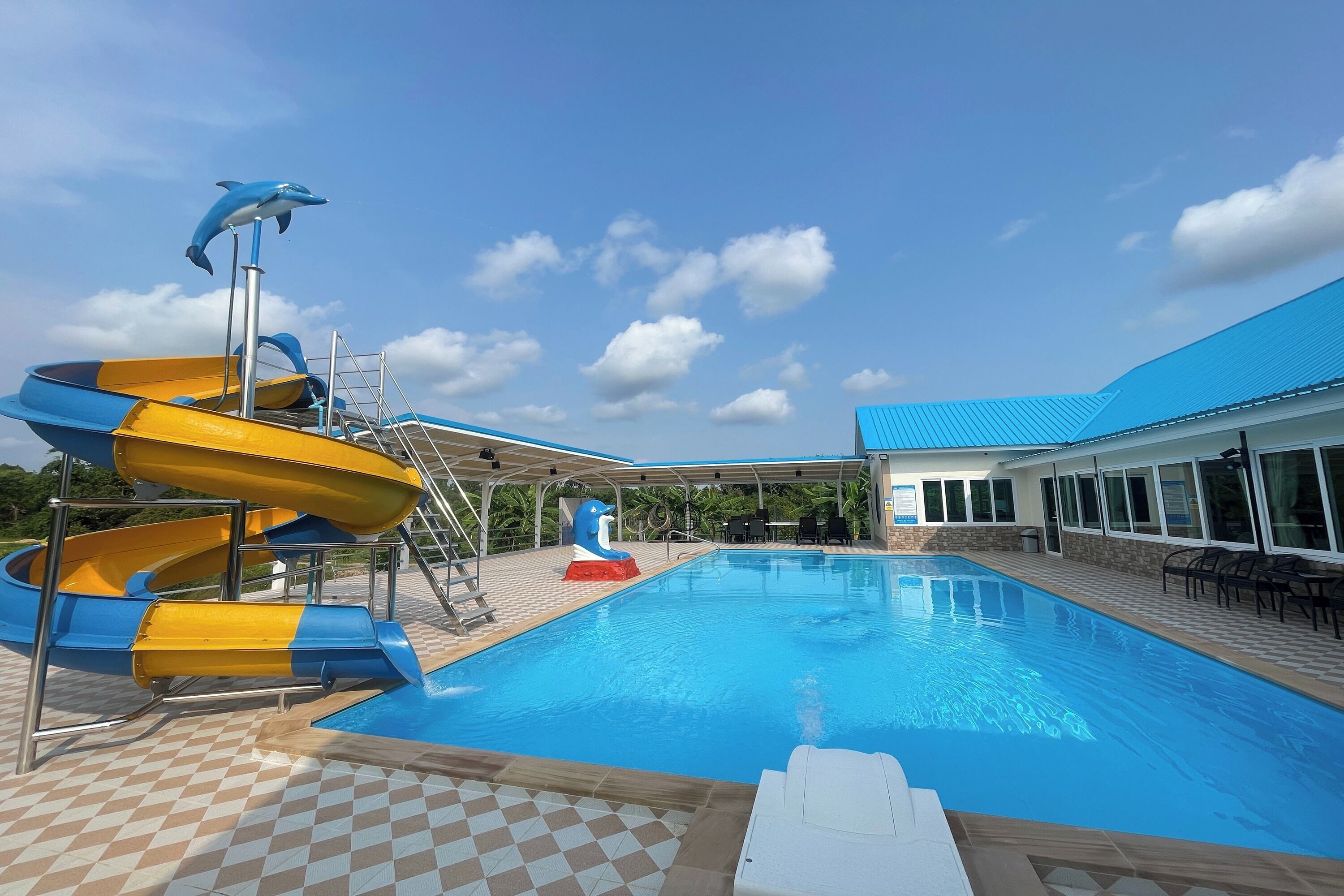 A swimming pool with slides, a covered area, and a building with a blue roof.