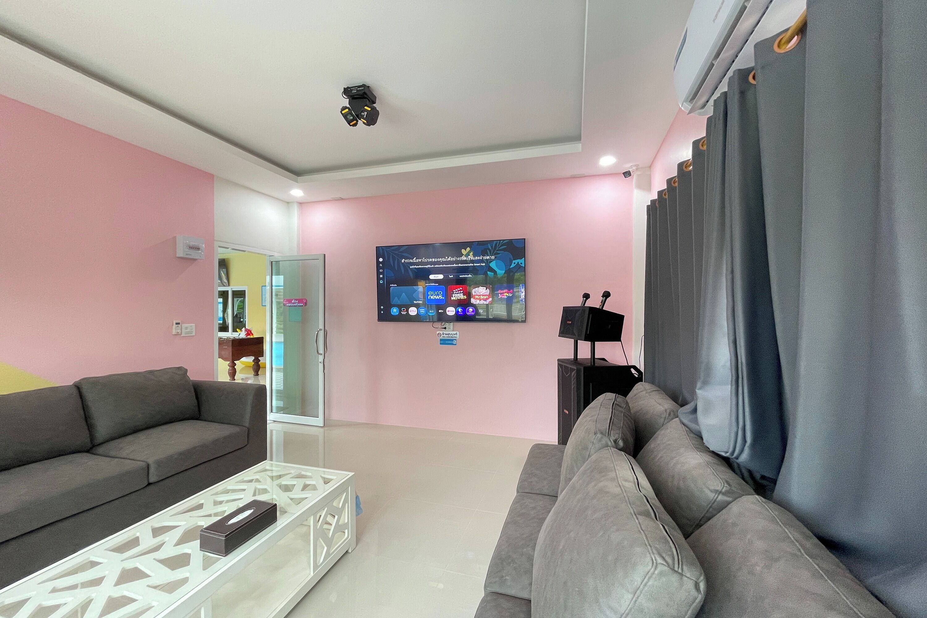 A living room with a grey sofa, a white coffee table, and a flat-screen TV mounted on the wall.