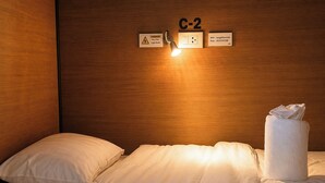 A hotel room with a bed, a sign indicating room number C-2, a light switch, a WiFi password sign, and a towel on the bed. - Lazy Gibbon 2 Chiang Mai - Haiya (Chiang Mai)