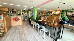 A hostel interior with a wooden reception desk, seating area, and a mural of a monkey. - Lazy Gibbon 1 Chiang Mai - Tha Phae Gate (Chiang Mai)