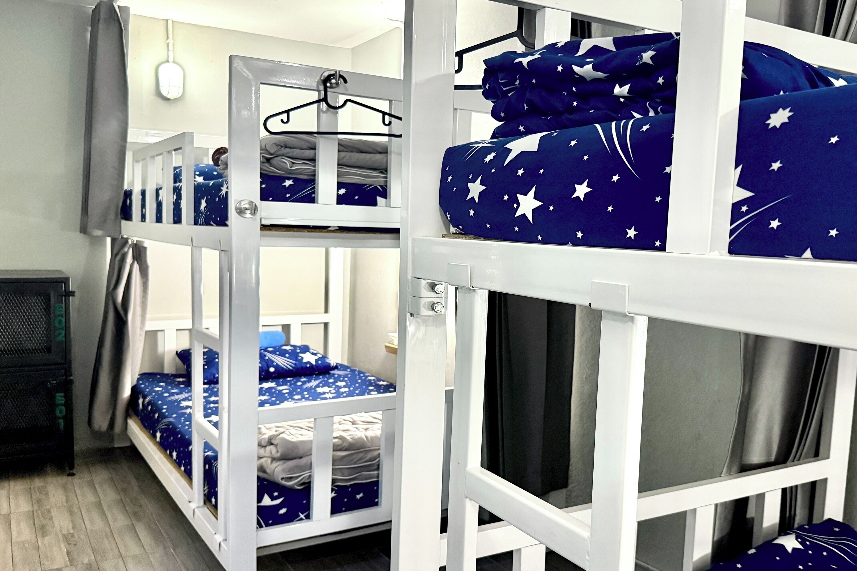 Dormitorio con literas, una lámpara colgante, una mesita pequeña y una ventana con cortinas.