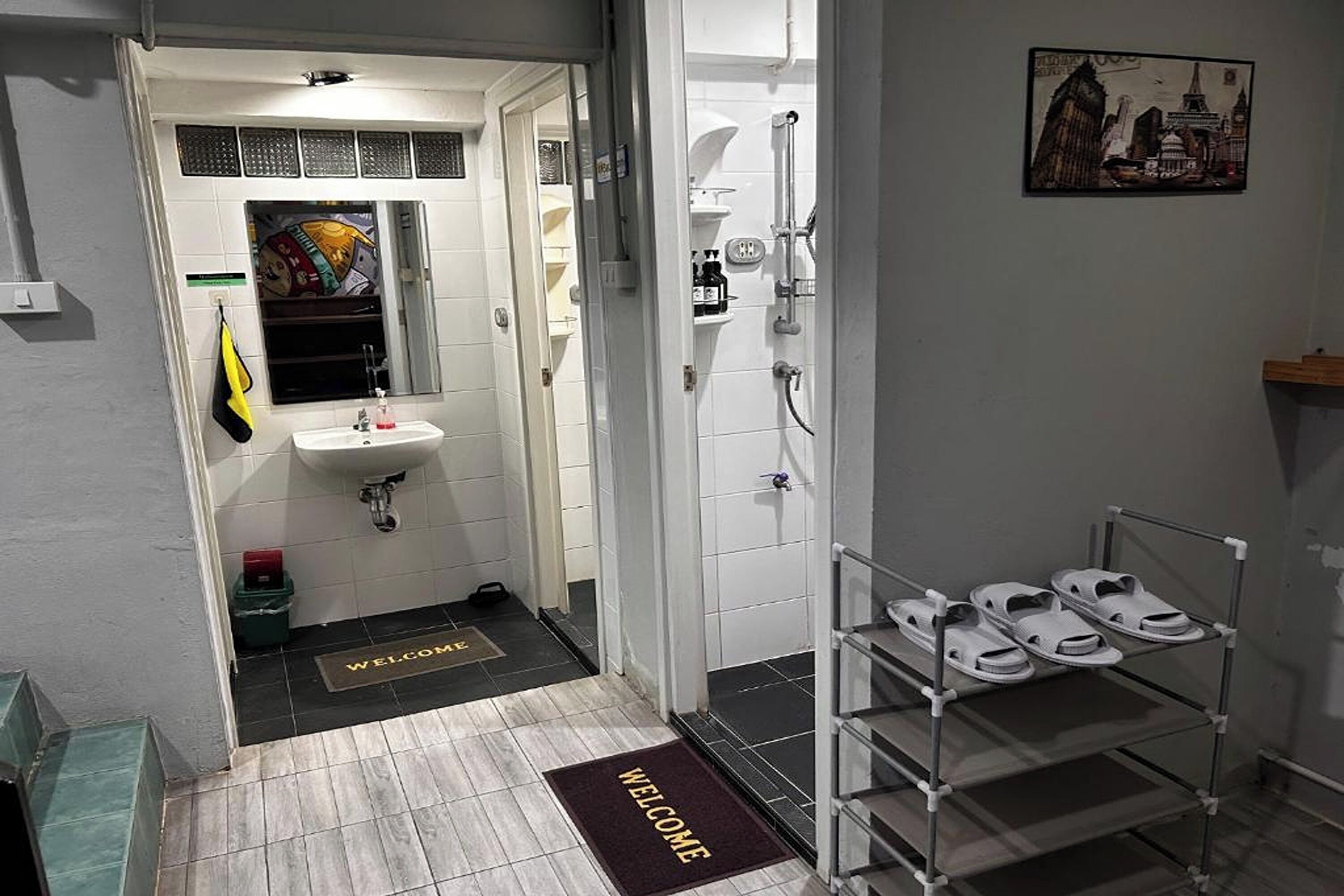 A bathroom with a sink, shower, and a rack of white slippers.