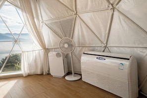 Une pièce dotée d’une grande fenêtre, d’un ventilateur sur pied et d’un appareil de climatisation.
