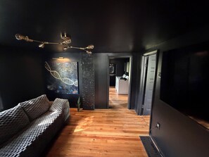 Un intérieur moderne avec un plancher en bois, un canapé, un tableau et une cuisine en arrière-plan.
