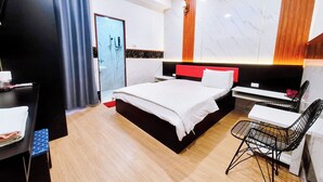 Ein Hotelzimmer mit Bett, Schreibtisch, Stuhl, Kleiderschrank und Klimaanlage.