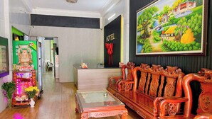 A reception area with a wooden sofa, a glass-top coffee table, and a painting of a landscape. - Phuc Khang Airport Hotel (Ho Chi Minh City)