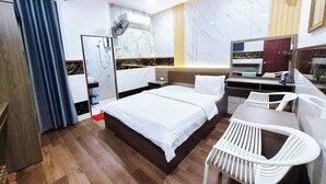 A hotel room with a bed, a desk, a chair, a mirror, a wardrobe, and a shower area. - Phuc Khang Airport Hotel (Ho Chi Minh City)