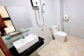 Kylpyhuone, jossa on valkoinen pesuallas, lasihylly, wc ja suihkukaappi.