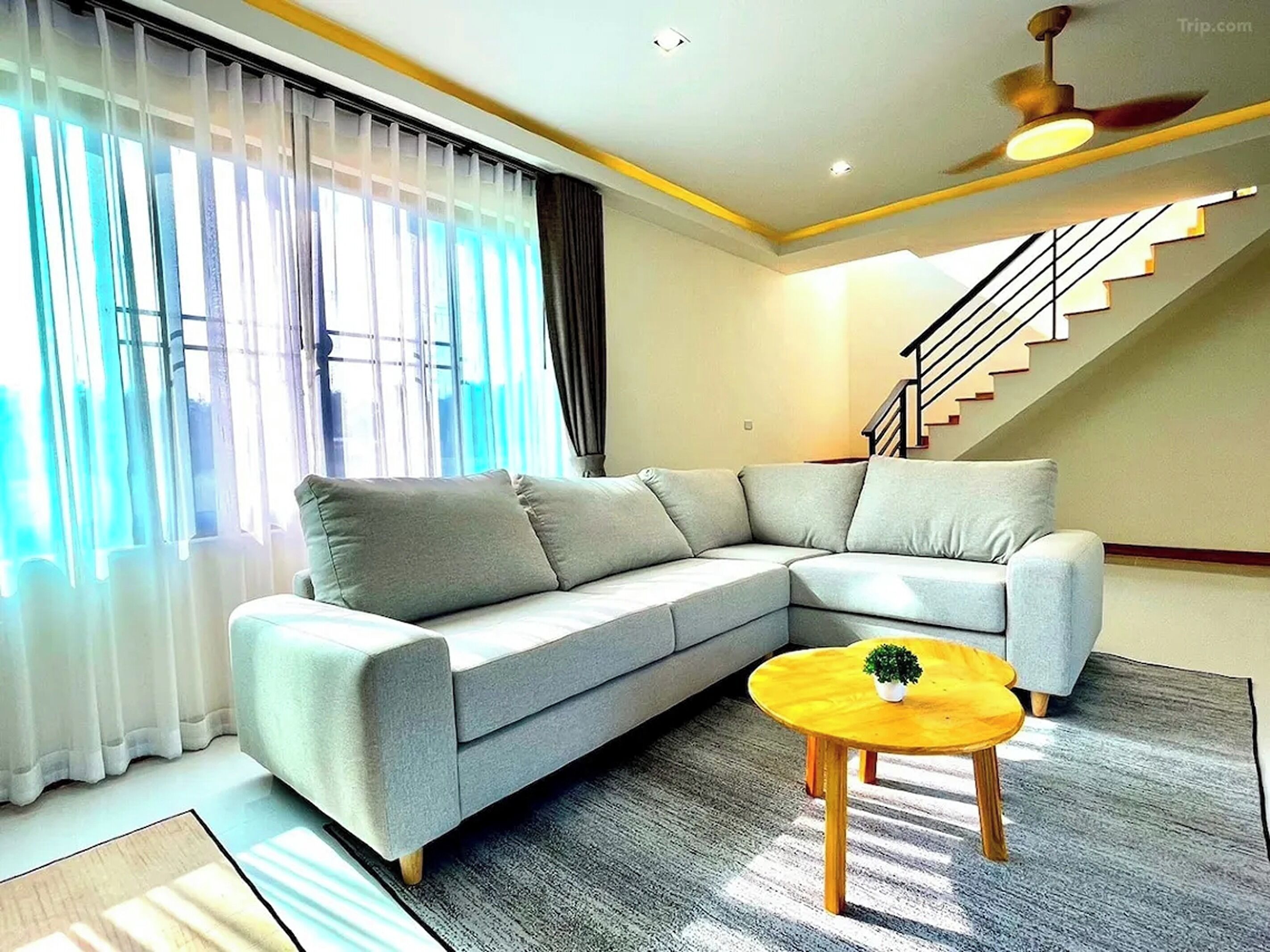 A modern living room with a grey sectional sofa, a small wooden coffee table, and a staircase leading to an upper floor.
